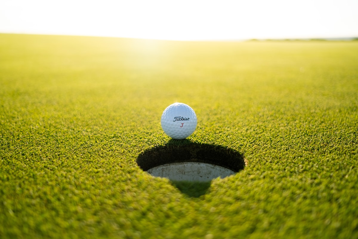 A Titleist ball resting on the lip of the hole